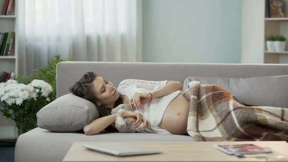 Expecting Woman Lying on Couch With Teddy Bear, Thoughts About Her Future Child