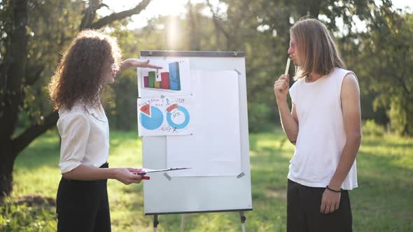 Caucasian Man and Woman Arguing Discussing Business Strategy Analyzing Graphs in Sunshine in Spring