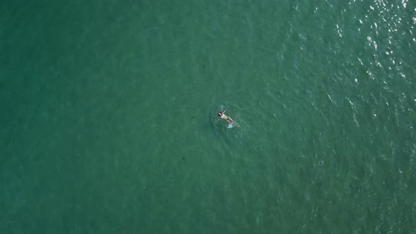 Beautiful woman in a bikini swims on her back in the Aegean Sea; Paros island, Greece; rotating aeri