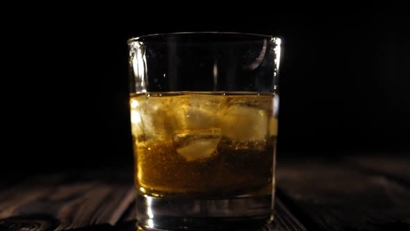 A Glass of Whiskey with Ice on a Wooden Background with Artificial Lighting
