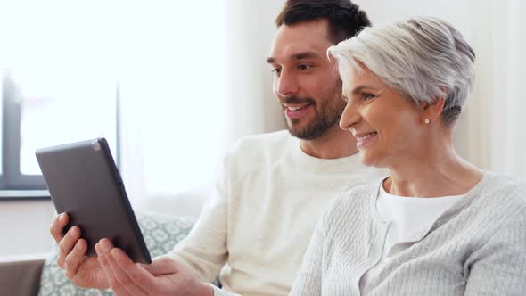 Old Mother and Adult Son with Tablet Pc at Home