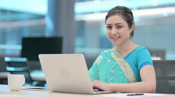 Indian Woman Smiling at Camera while using Laptop