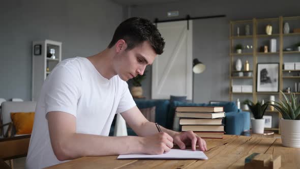 Man Writing on Papers While Sitting on Desk