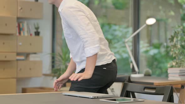 Young Man Closing Laptop and Leaving Modern Office