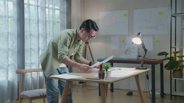 Side View Of Asian Man Designer Is Arranging The Layout Bond On The Table At The Office