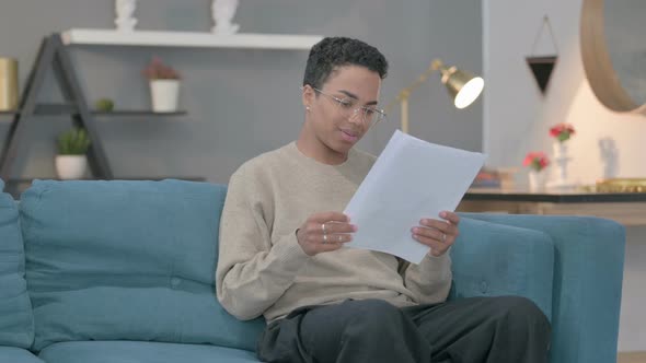 African Woman Having Success on Documents Sofa