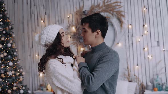 Portrait of a Young Couple Dancing at Home in the Living Room Next To a Decorated Christmas Tree