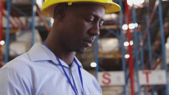 Portrait of a young man wearing a hard hat in a warehouse 4k