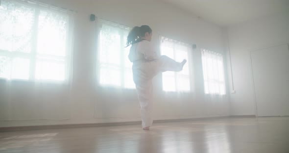 Slow motion footage of a girl practicing martial arts in a dojo