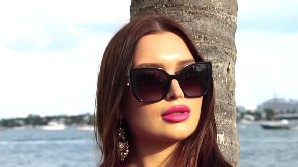 Pretty Young Female Model With Sunglasses by Palm Tree on Sunny Day, Slow Motion