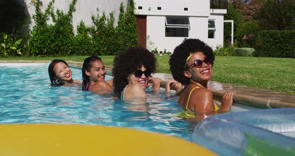 Diverse group of female friends standing at the poolside looking at the camera