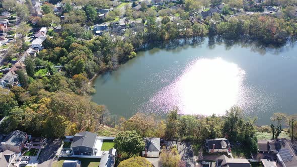 An aerial drone view of Grant Pond in a Long Island, NY suburb. The camera truck right & is tilted d