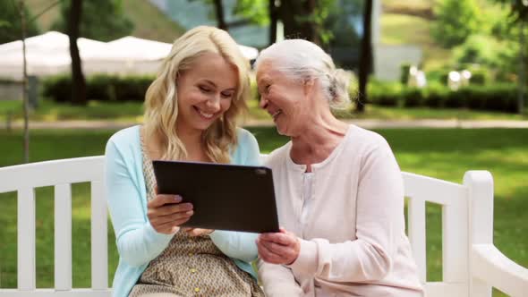 Daughter with Tablet Pc and Senior Mother at Park