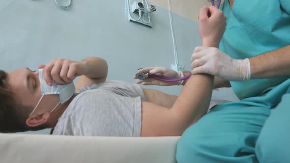 Doctor Exams Male Patient with Stethoscope Looks for COVID19 Symptoms