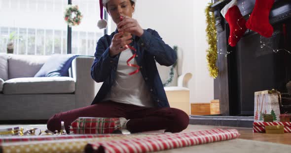  Woman in Santa hat wrapping Christmas presents at home