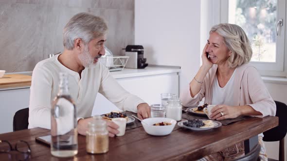 Affectionate mature couple at table in kitchen