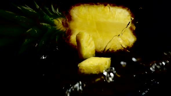 Falling juicy pieces of pineapple on a black background. Slow motion.