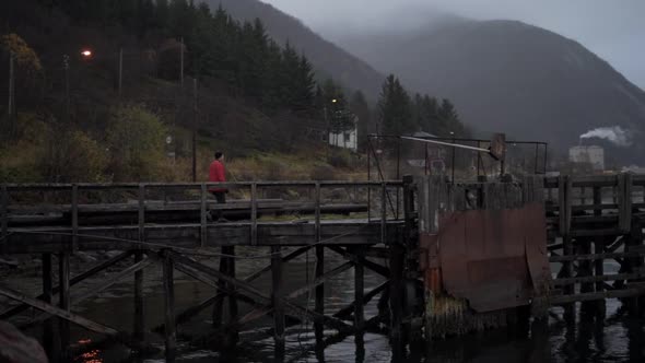 Hiker Walking Along Old Pier In Fjord