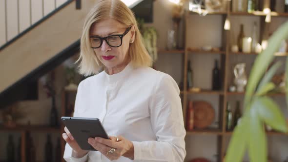 Senior Woman Working on Tablet in Restaurant