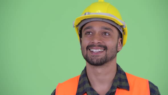 Face of Happy Young Bearded Persian Man Construction Worker Thinking