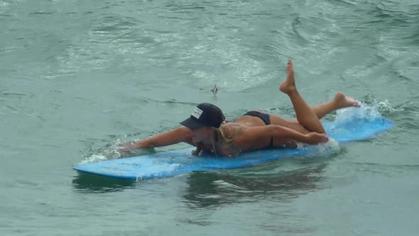 A young woman surfing in a bikini on a longboard surfboard.