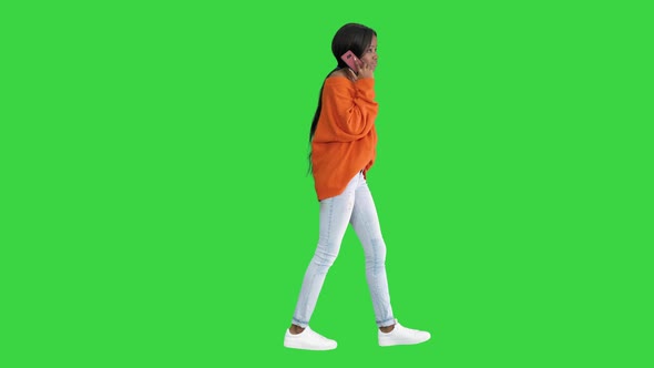 Emotional African American Woman in Bright Jumper Talking on the Phone While Walking on a Green