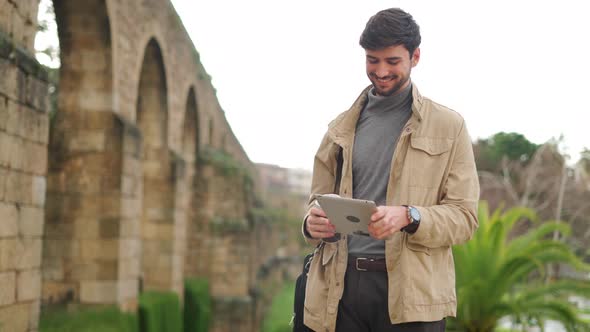 Man using tablet while standing on street near arched wall