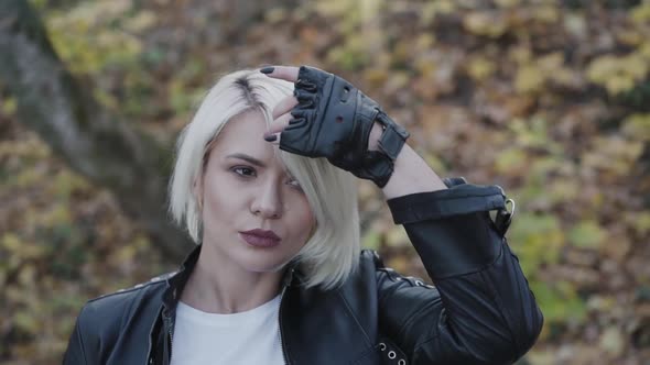 Portrait of Thoughtful Female Biker Corrects Her Hair in Park