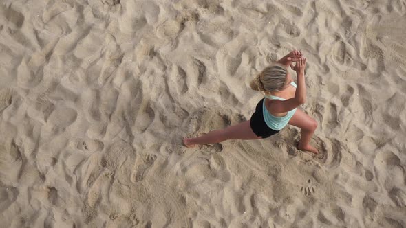 Overhead shot of a young attractive woman doing yoga on the beach