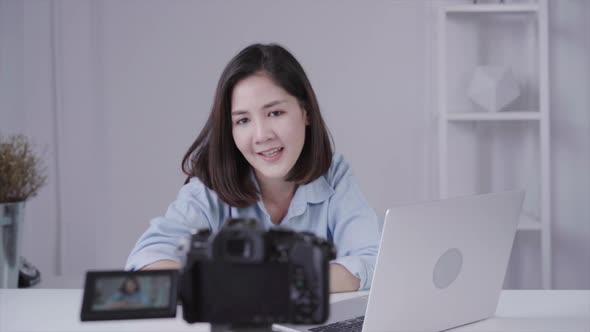 Asian woman answer question from her subscribers. Female blogger recording video with laptop
