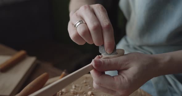 Woman Carpenter Polishes Wooden Spoon with a Sandpaper Close-up