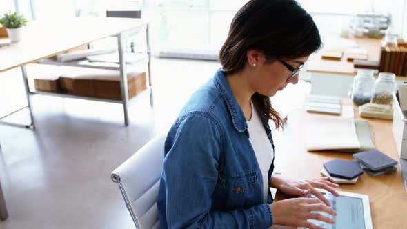 Female executive sitting at desk and using digital tablet