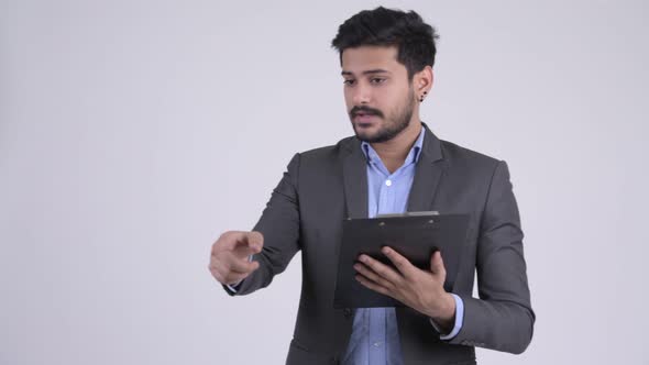 Young Bearded Indian Businessman Directing While Holding Clipboard