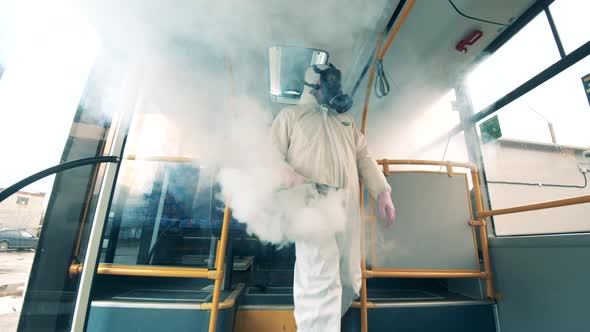 Sanitation Worker Disinfects Bus with a Sprayer.