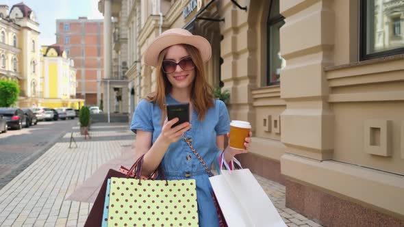 Young Woman with Shopping Bags Walking in a City at Summer Day