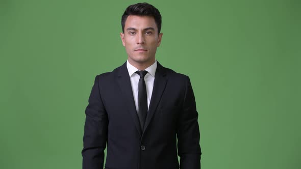 Young Handsome Hispanic Businessman Against Green Background