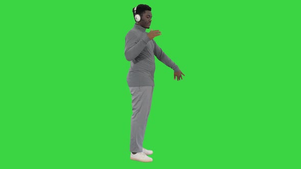 Passionate African American Man Listening To the Music in Headphones and Dancing on a Green Screen