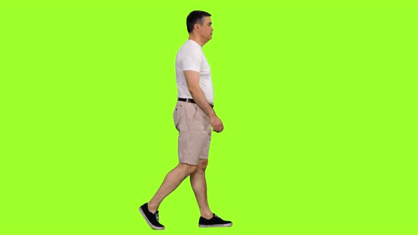 Adult Male in White T-shirt and Shorts Walks on Green Background