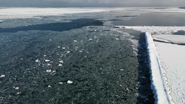 Rising drone shot over ice-covered pier on Lake Huron in Michigan