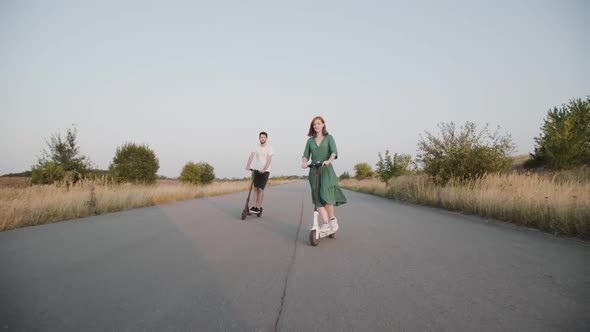 Girl and Boy Riding on Electric Scooters to the Camera and Having a Fun on Way