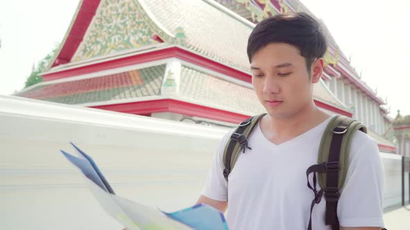 Young backpacker male looking on map find landmark while spending holiday trip.