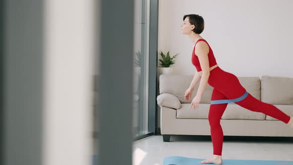 The Woman Is Doing Butt Exercise with a Fitness Band