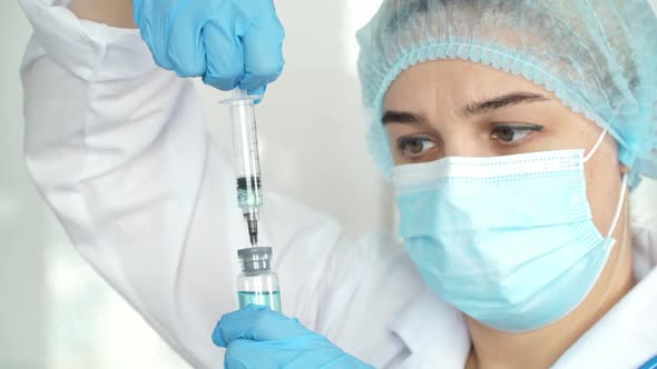 Nurse in Gloves White Coat and Mask Fills Syringe with Drug
