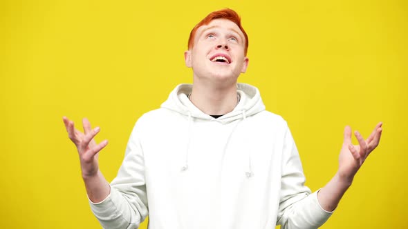 Excited Redhead Caucasian Young Man Looking Up Smiling with Hands Up