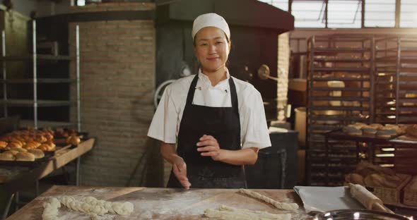 Animation of happy asian female baker cleaning hands from four and smiling at camera