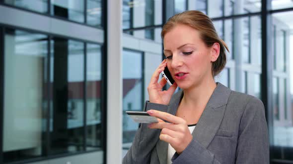 Businesswoman using credit card while talking on mobile phone