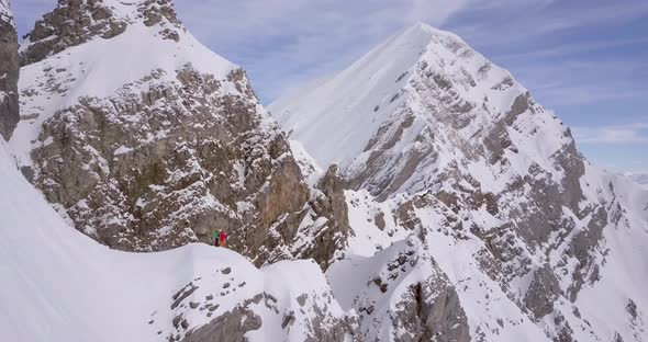 Aerial drone view of a skier skiing down a steep snow covered mountain.