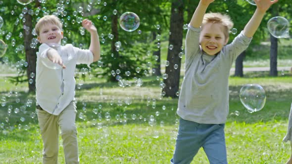 Cute Boys and Girls Catching Soap Bubbles