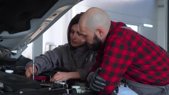 Two Professional Mechanics Female and Male Repairing a Car in Car Repair Shop. Car Service, Repair