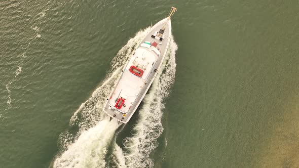 A top down shot over a fishing boat heading out to sea on a cloudy morning. The drone camera follows